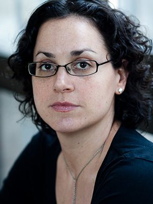 A woman with glasses and curly hair wearing a black shirt.