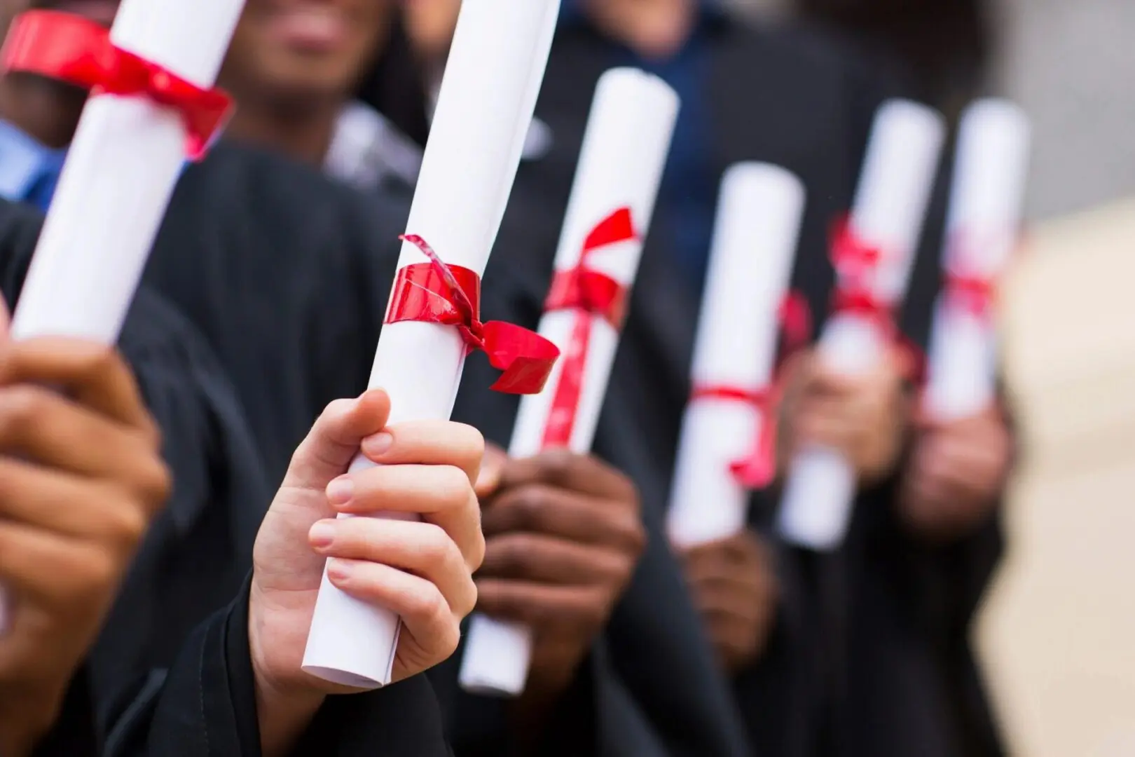 A group of people holding up diplomas in their hands.