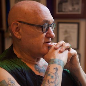 A bald man with tattoos on his arms and head.