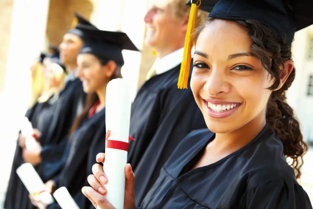 A group of people in graduation attire holding their diplomas.