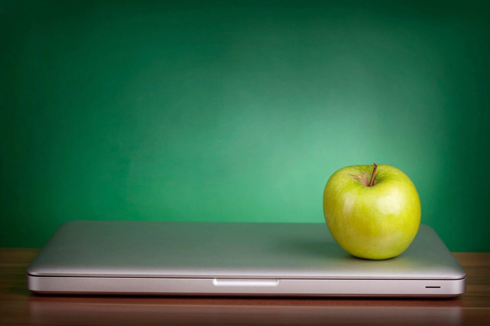 A green apple sitting on top of a laptop.