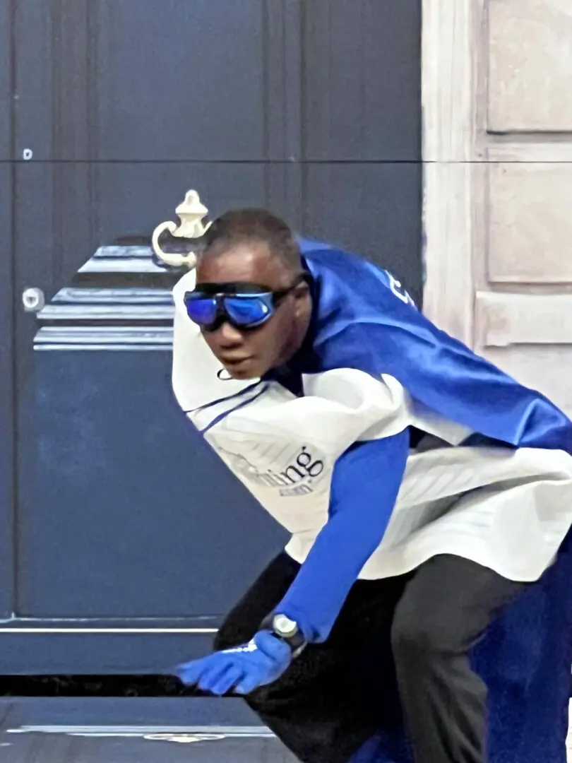 A man in blue and white cape riding a bike.