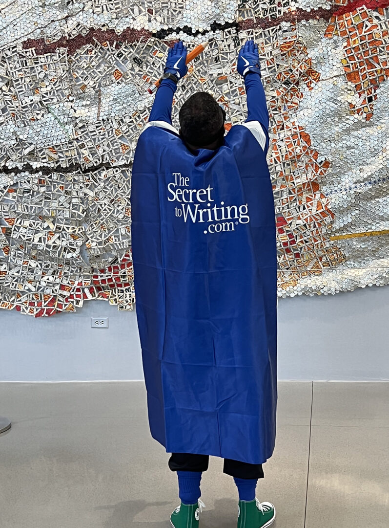 A person in a blue cape holding up their arms.