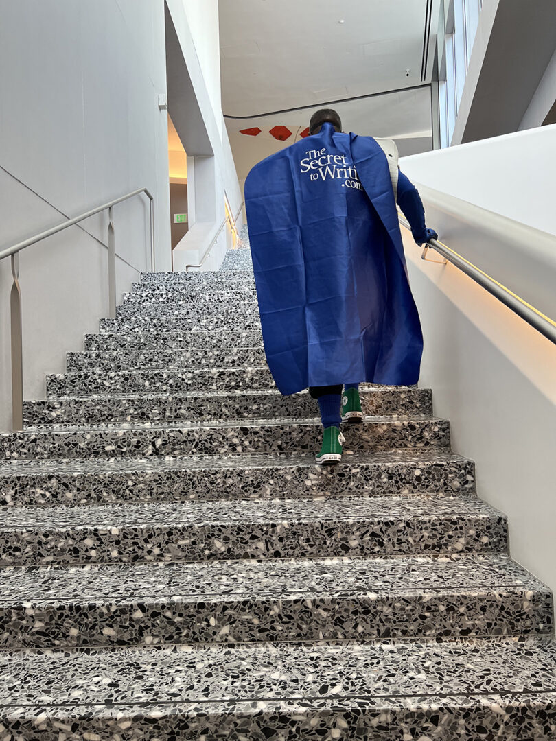 A person in a blue cape walking up some stairs