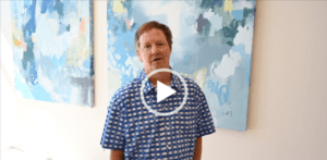 A man standing in front of a painting with an animated video button.