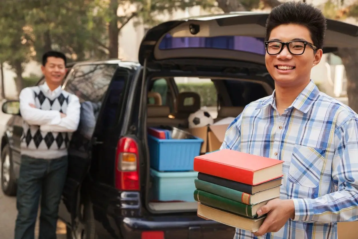 A man holding books in his hand while standing next to a car. A man holding books in his hand while standing next to a car.