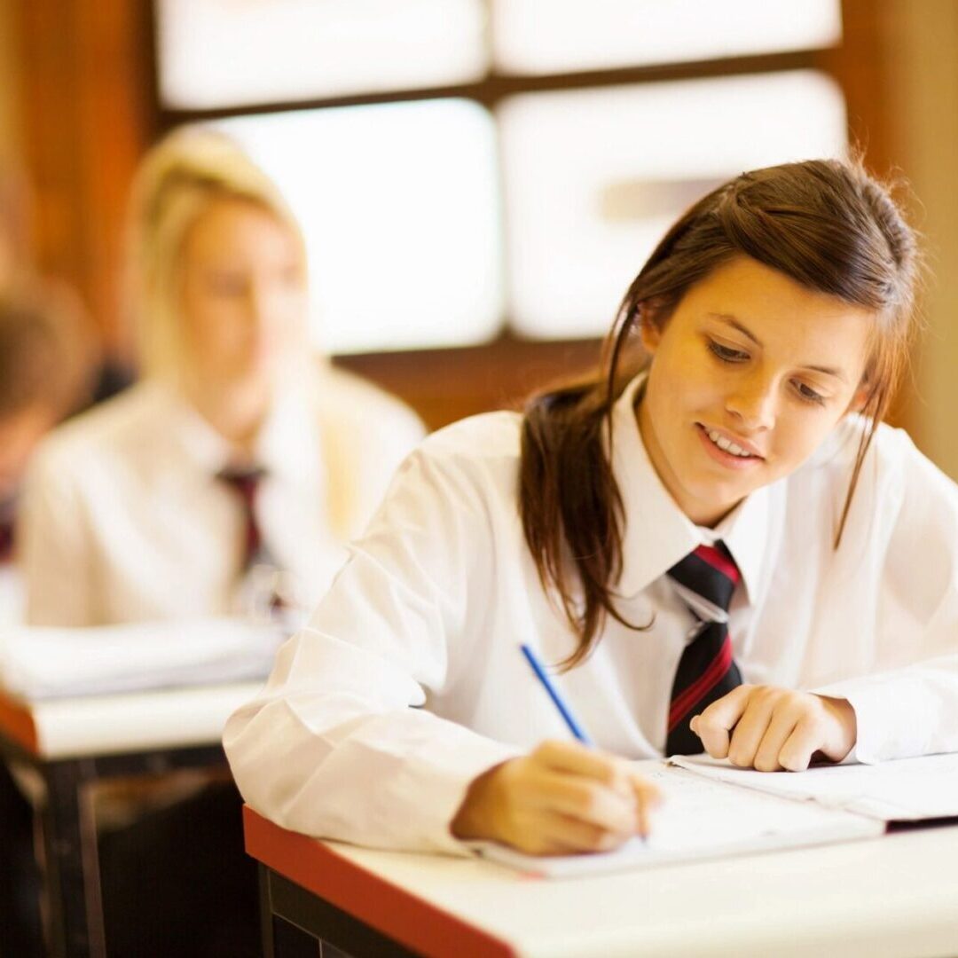 A girl in school uniform writing on paper.