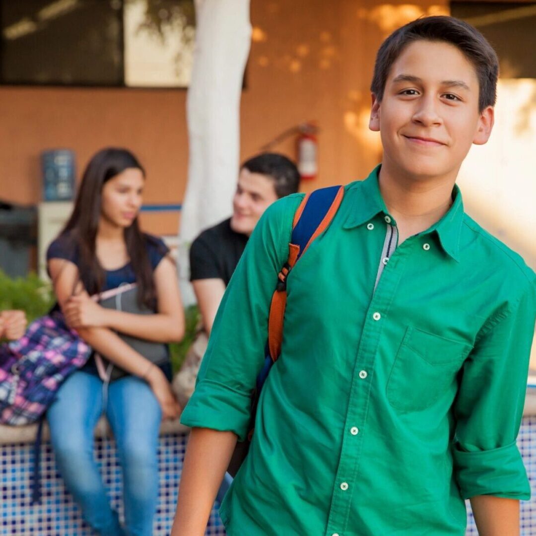 A young man in green shirt holding a blue bag.